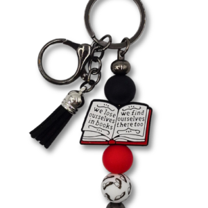 Elegancki breloczek, zawieszka do torebki lub plecaka z motywem książkowym i napisem: We lose ourselves in books we find ourselves there too. W kolorach czarnym, białym i czerwonym. Idealny na prezent dla miłośnika książek