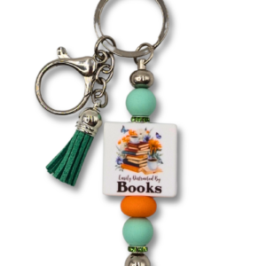 Breloczek z koralikami w kolorze mięty i pomarańczowym. Z napisem: Easlu Distracted by Books i ozdobny frędzel