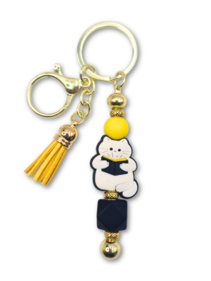 bag charm breloczek z kotem czytającym książkę w kolorze biało czarno żółtym dla miłośników białych kotów i czytania