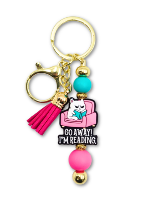 zabawny breloczek z kotem i napisem go away i'm reading dla książkar i miłośniczek kotów na prezent